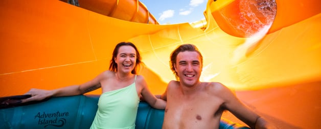 A woman and man smiling and riding Wahoo Remix water slide